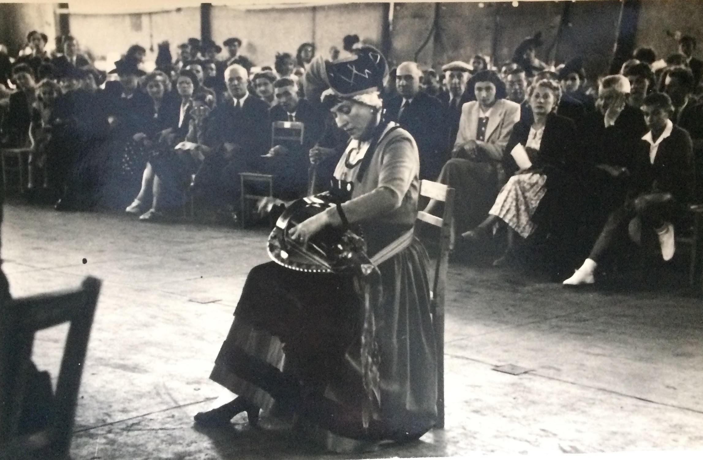 La vielleuse Germaine Bertrand auditionne entre le jury et l'assistance, dans la halle de St-Amand Montrond, 14 août 1950 (Photo Rousseau pour Le Berry Républicain)